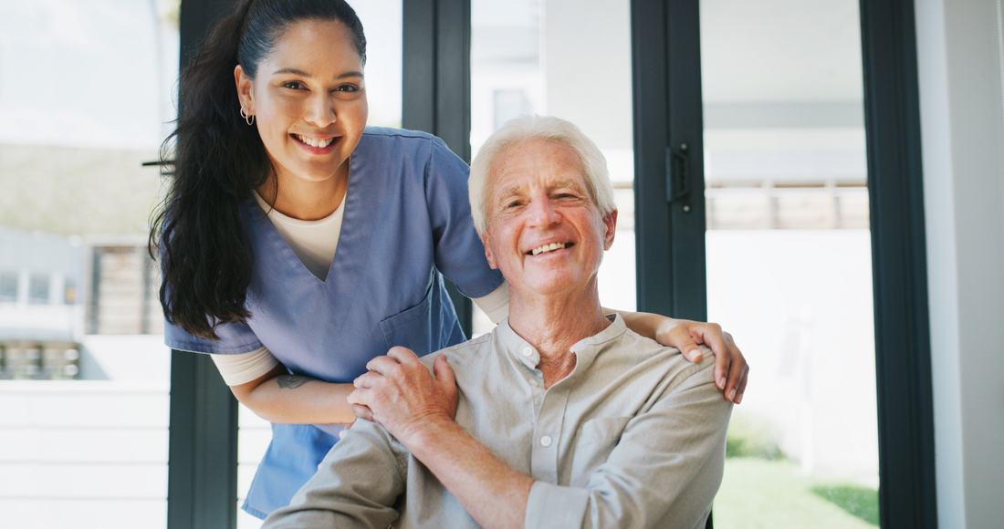 A uniformed caregiver and senior client smiling together